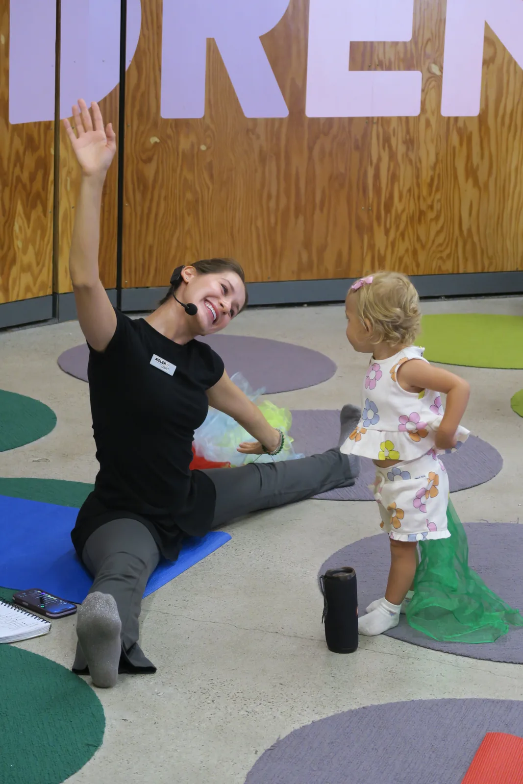 Marit demonstrating a seated side stretch beside a young child.