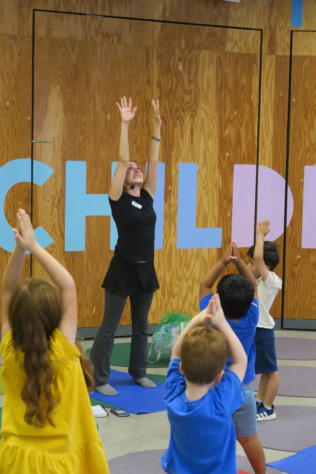 Marit and children reaching their arms overhead during a movement class.