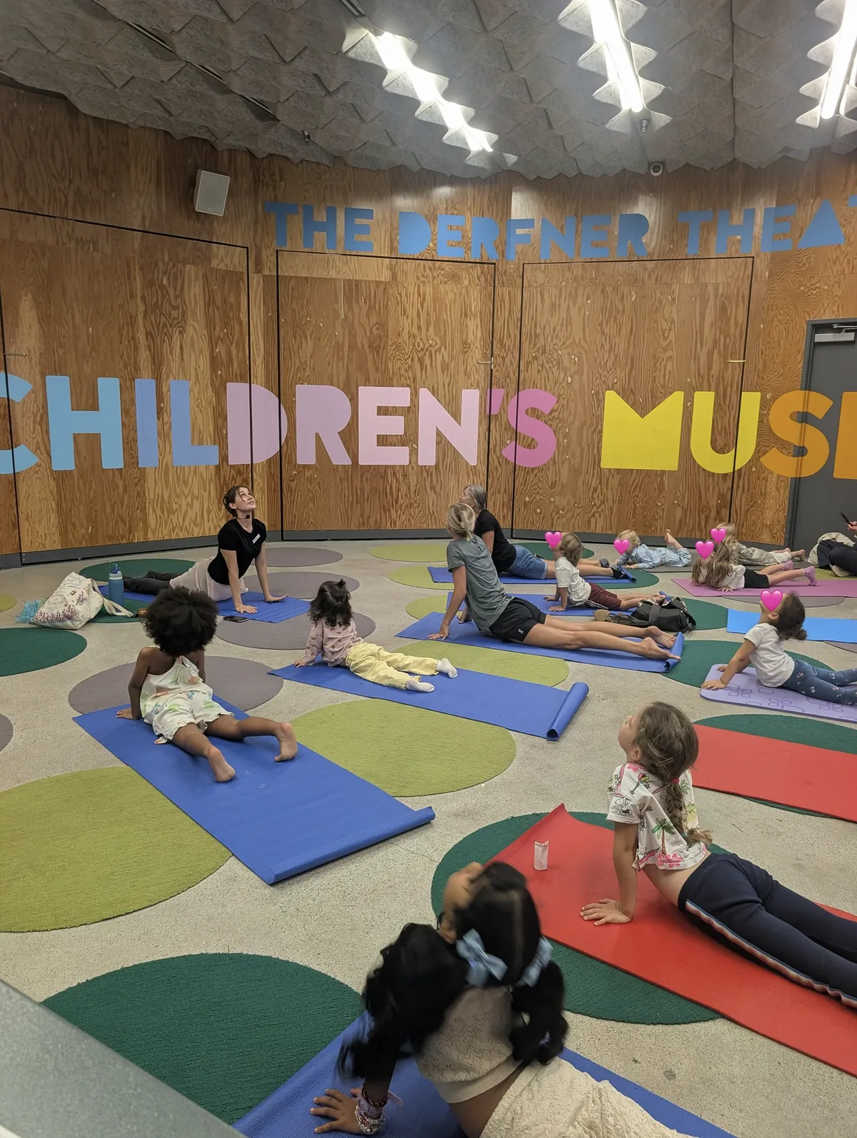 Children and adults stretching on colorful yoga mats during a group class.